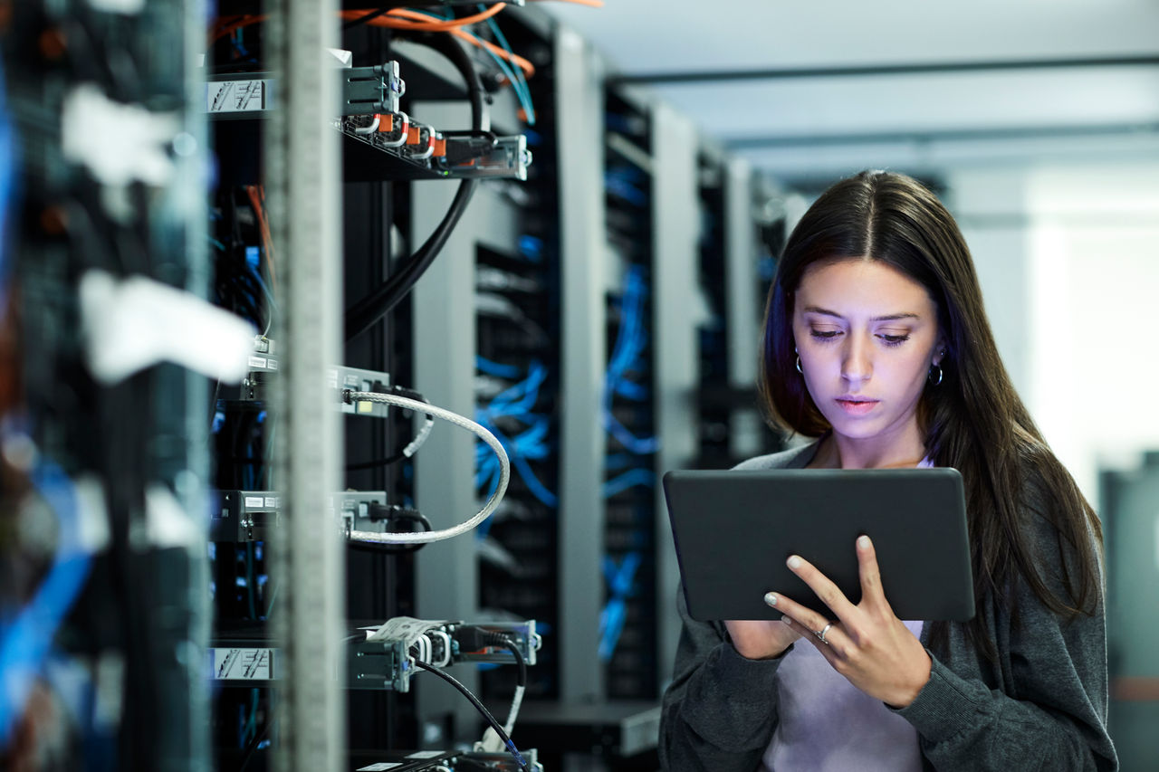 A network engineer holding a tablet and working in a data center. 